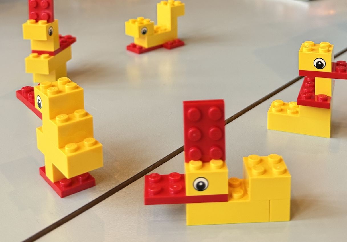 Five different ducks built from the same bricks on a workshop table